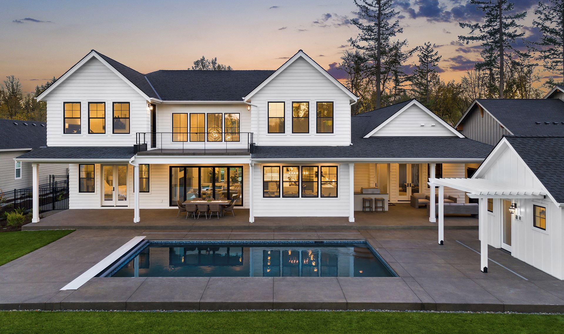 Rear view of a gorgeous custom home with pool at sunset